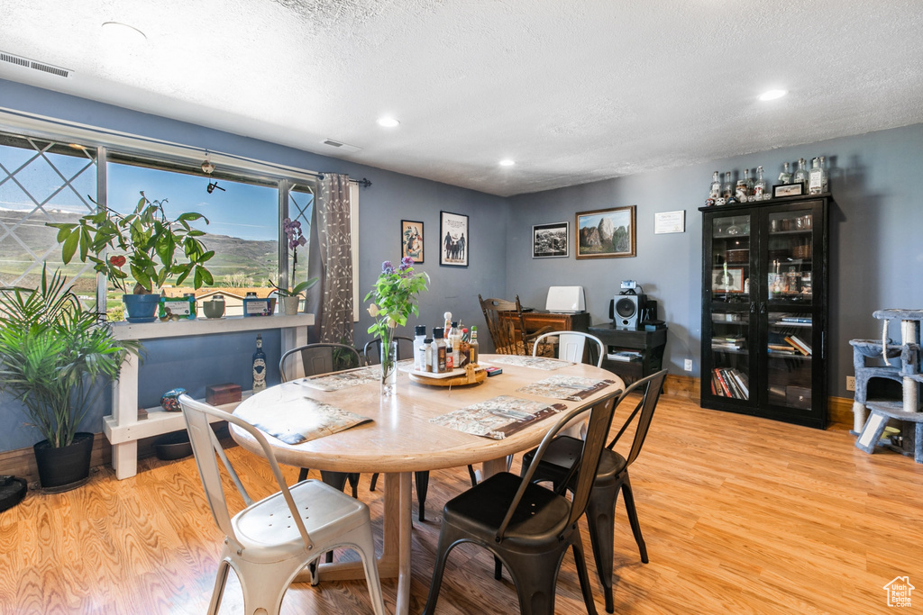Dining area with light wood-type flooring, recessed lighting, and a textured ceiling