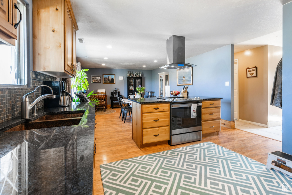 Kitchen with stainless steel electric range, island range hood, light wood-type flooring, tasteful backsplash, and recessed lighting