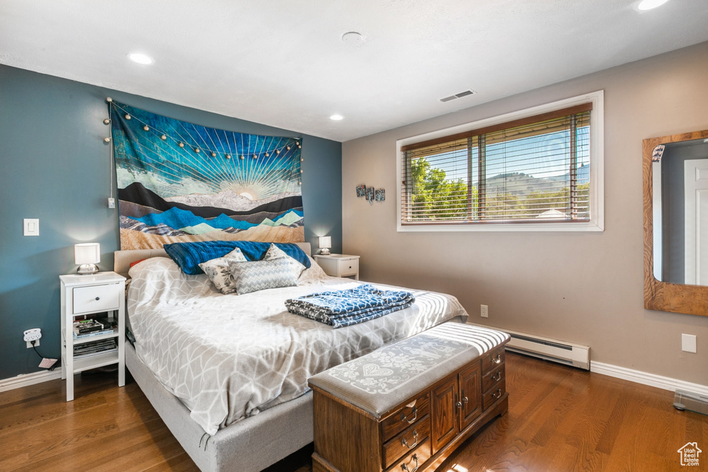 Bedroom featuring wood finished floors, a baseboard heating unit, and recessed lighting