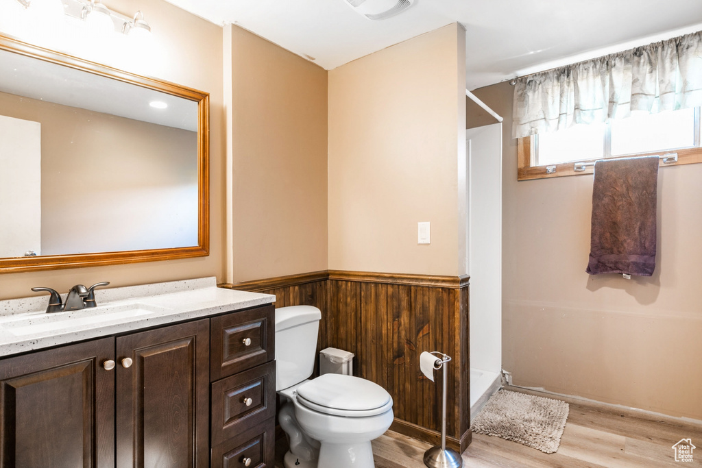 Full bath with wood finished floors, a stall shower, vanity, a wainscoted wall, and wood walls