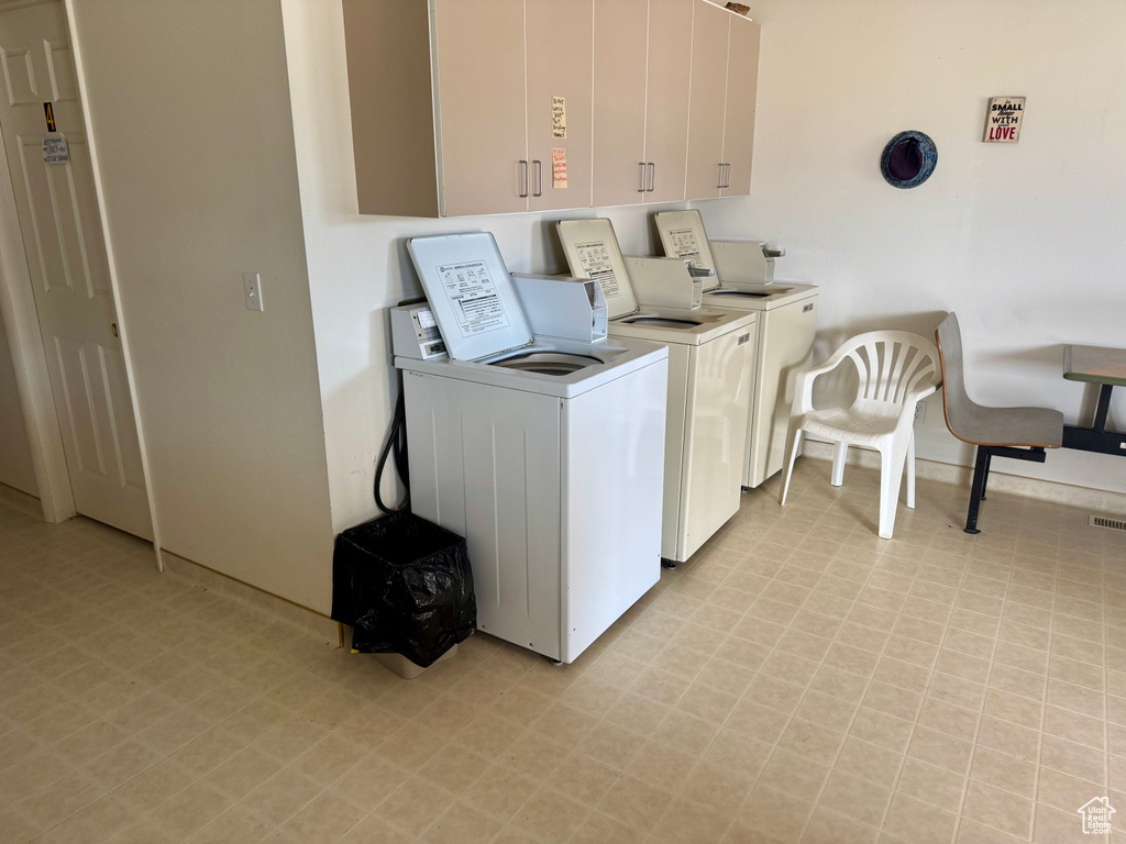 Communal laundry room featuring light floors and washing machine and dryer