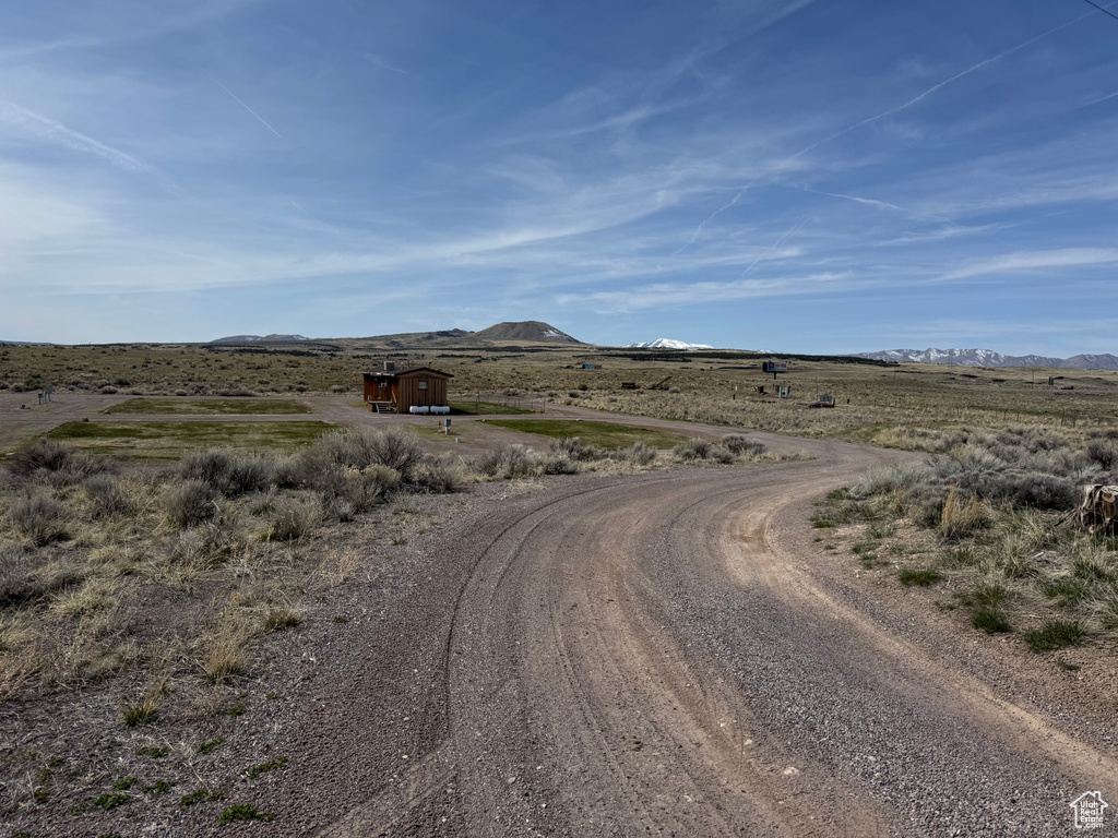 View of dirt / gravel road with a mountain view and a view of countryside