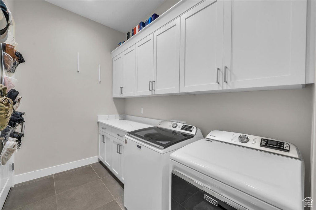 Laundry room with cabinet space, washer and clothes dryer, and dark tile patterned floors