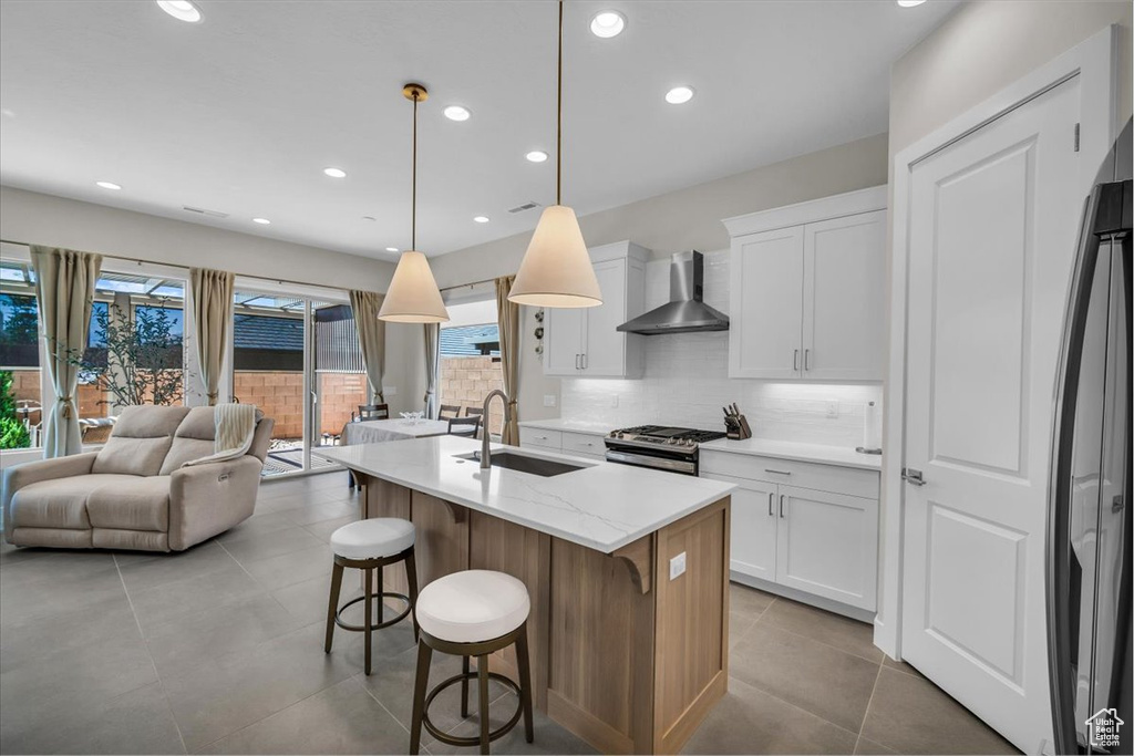 Kitchen featuring wall chimney exhaust hood, appliances with stainless steel finishes, healthy amount of natural light, open floor plan, and recessed lighting