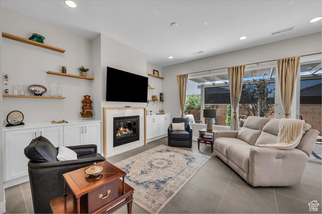 Living room with a glass covered fireplace, recessed lighting, and light tile patterned floors