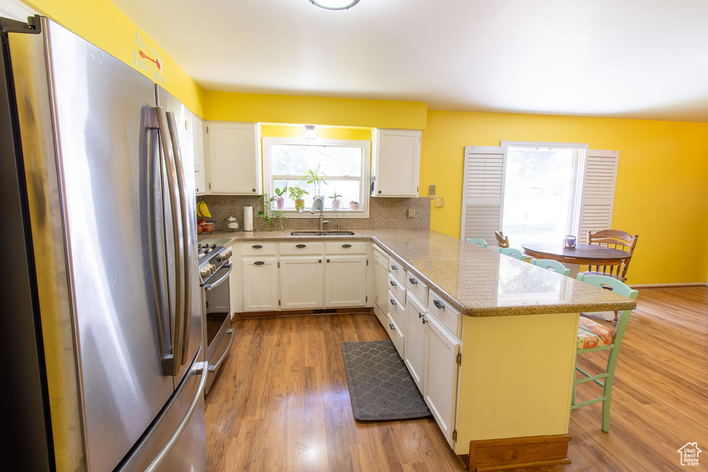 Kitchen with stainless steel appliances, a peninsula, a kitchen bar, and backsplash