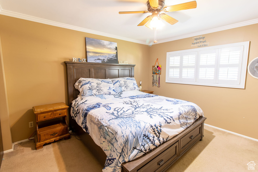 Bedroom with light colored carpet, ornamental molding, and ceiling fan