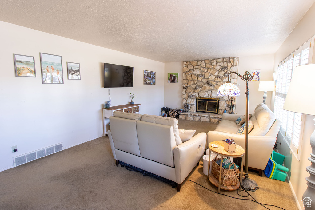 Carpeted living area with a stone fireplace and a textured ceiling