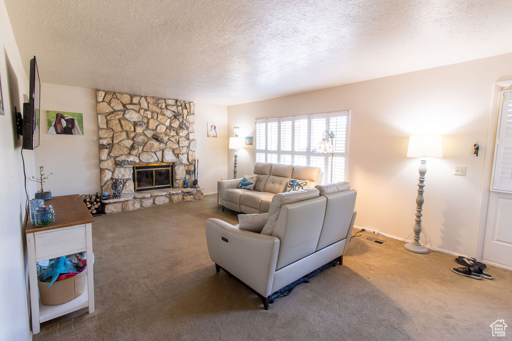 Carpeted living area with a textured ceiling and a stone fireplace