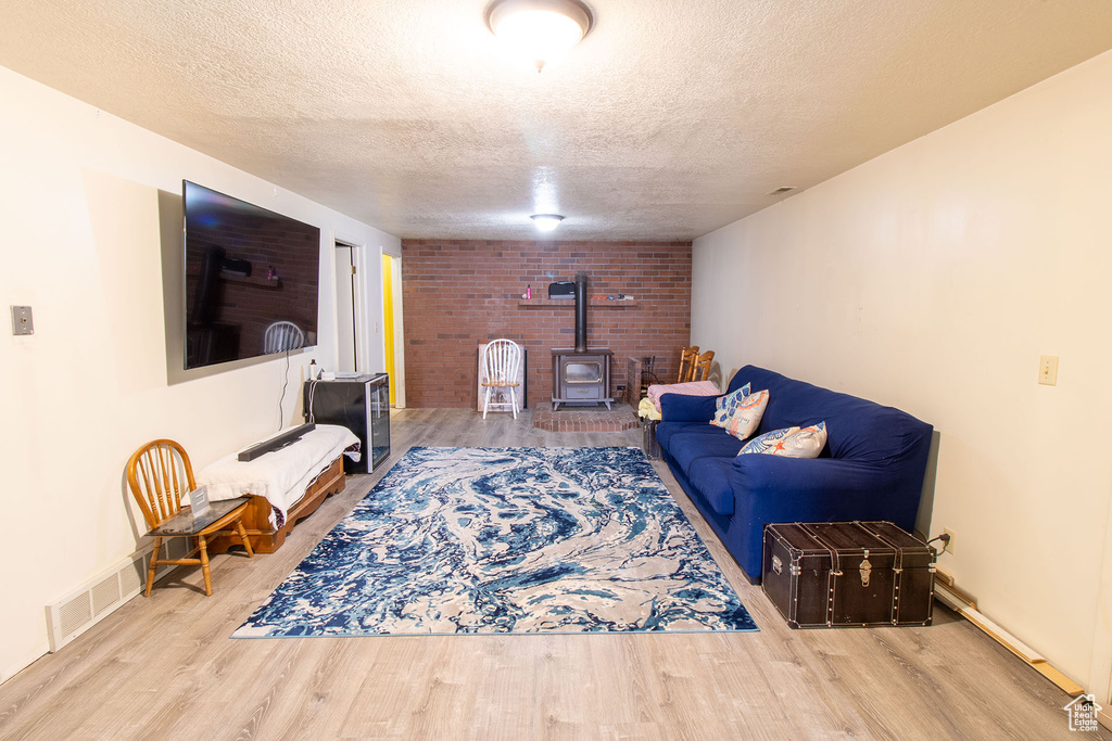 Living area featuring a wood stove, a textured ceiling, and wood finished floors