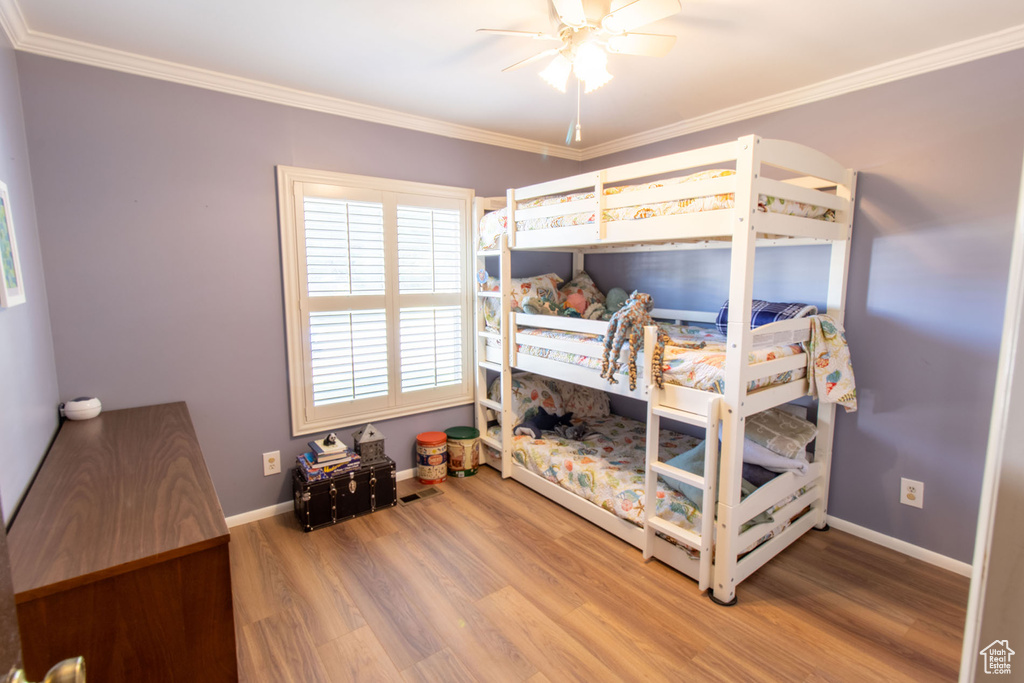 Bedroom with wood finished floors, ornamental molding, and ceiling fan