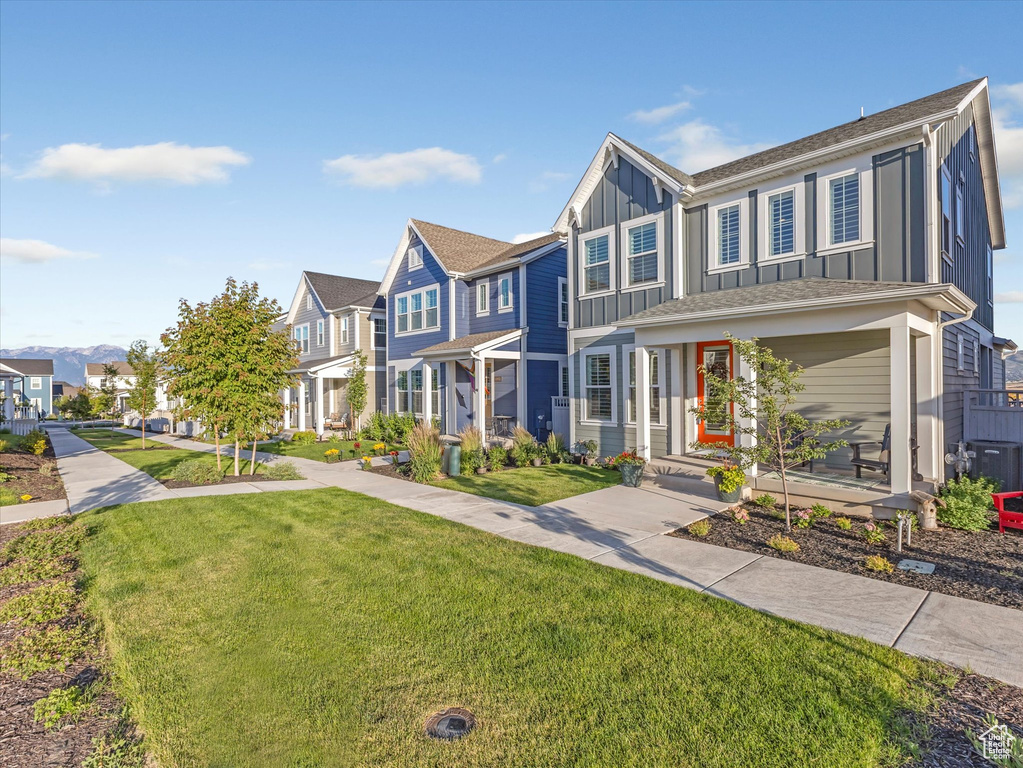Townhome / multi-family property with board and batten siding, a residential view, and a front lawn