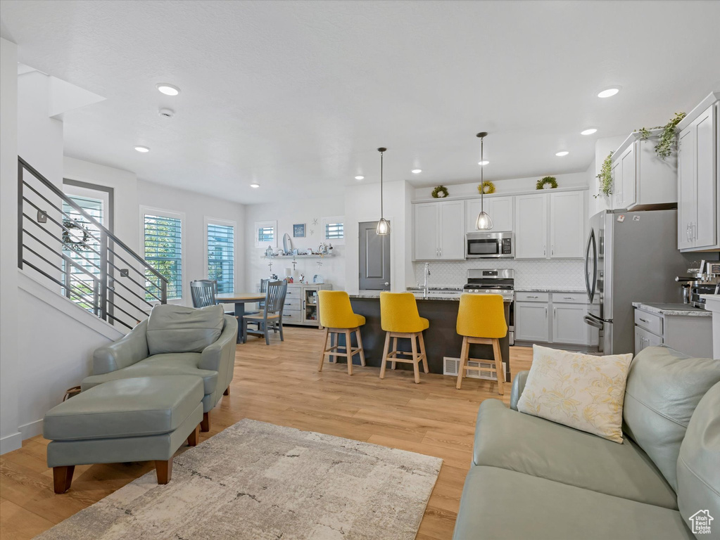 Living area with light wood-type flooring and recessed lighting