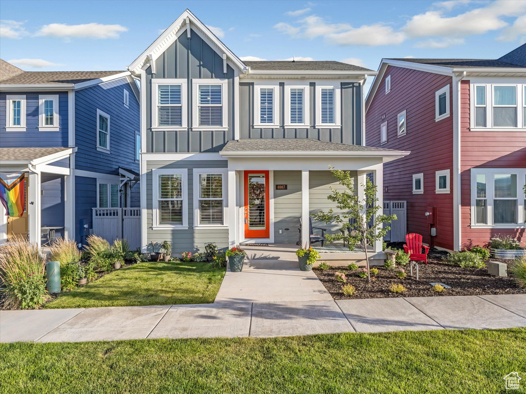 View of front of home with board and batten siding, covered porch, and a front yard