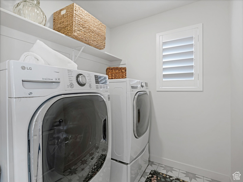 Laundry area with washer and dryer and light tile patterned flooring