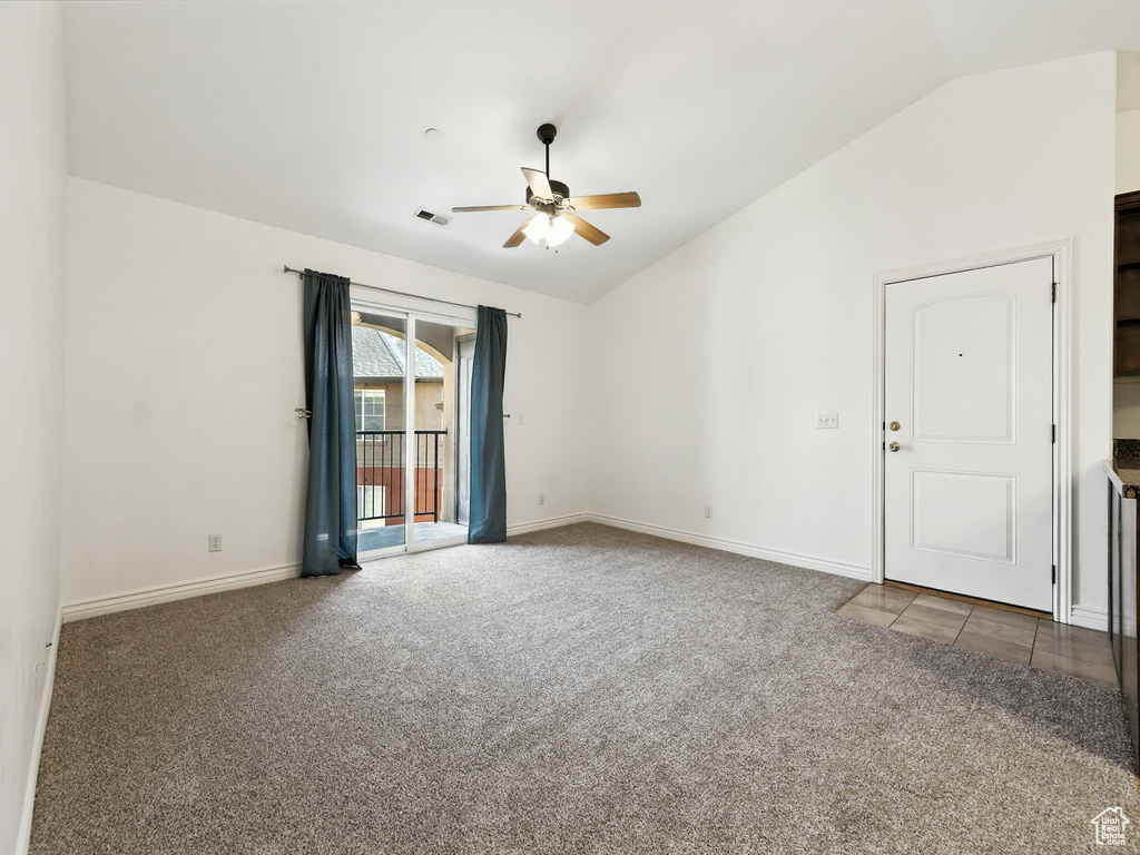 Spare room featuring vaulted ceiling, carpet, and ceiling fan