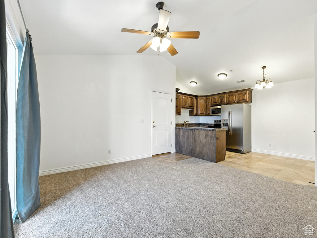 Kitchen featuring stainless steel appliances, dark countertops, a ceiling fan, open floor plan, and lofted ceiling