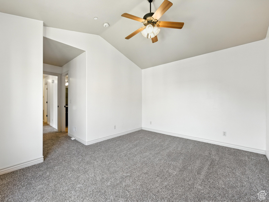 Spare room featuring carpet, lofted ceiling, and a ceiling fan