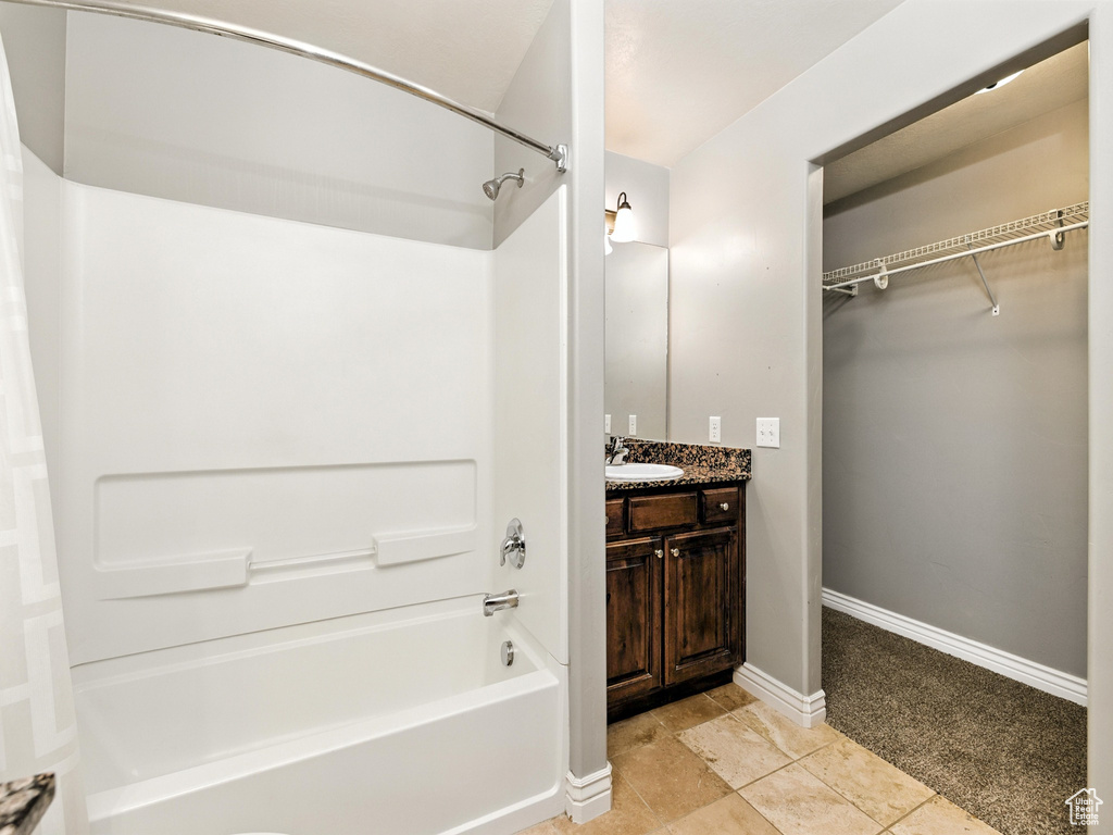 Bathroom featuring shower / bathtub combination, vanity, tile patterned flooring, and a walk in closet