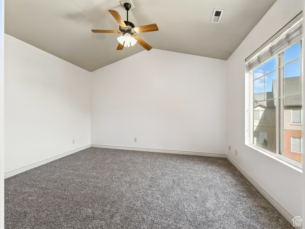 Spare room featuring carpet, ceiling fan, and vaulted ceiling