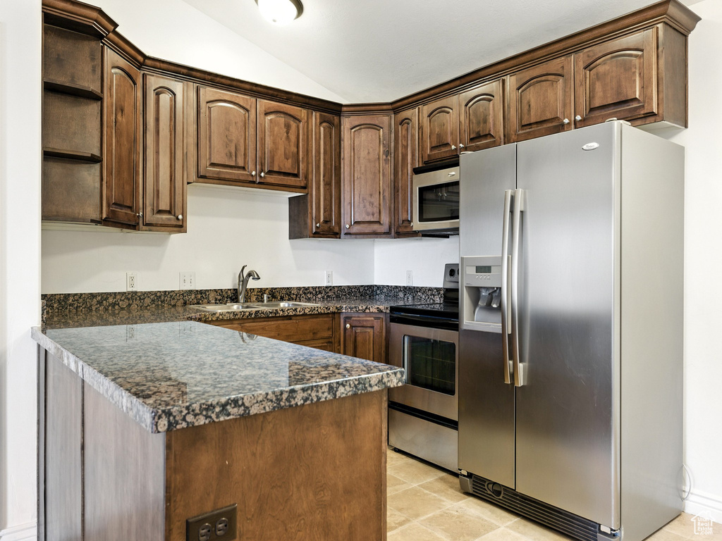 Kitchen featuring appliances with stainless steel finishes, dark countertops, open shelves, vaulted ceiling, and dark brown cabinetry
