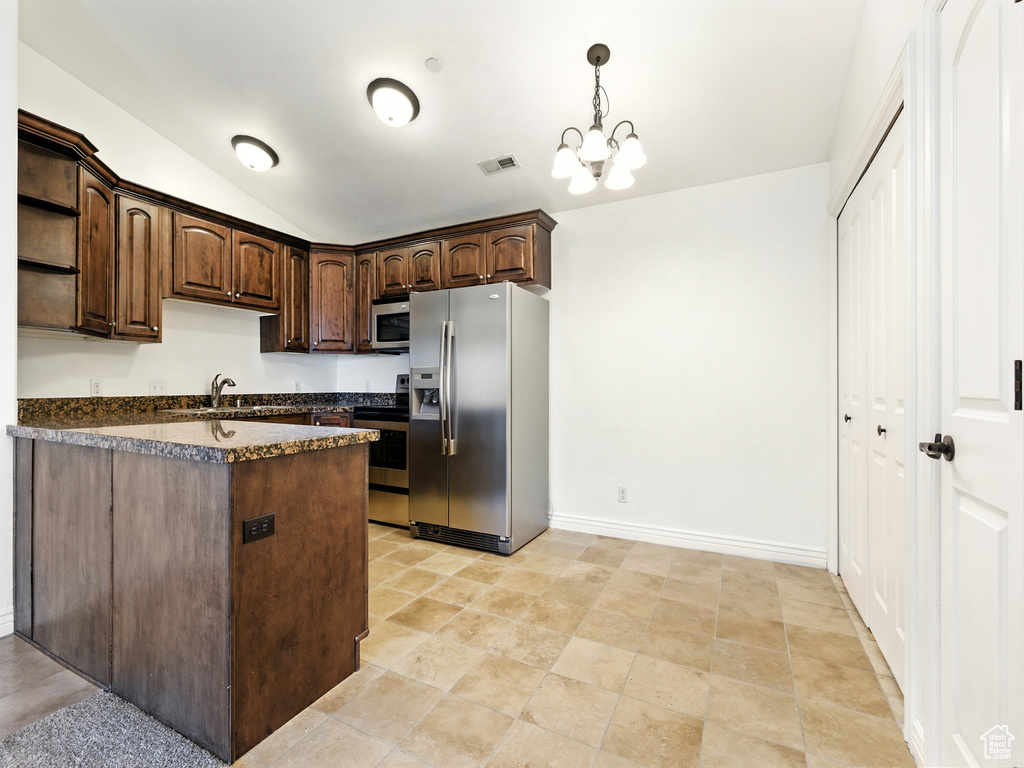 Kitchen with stainless steel appliances, dark countertops, dark brown cabinets, open shelves, and lofted ceiling