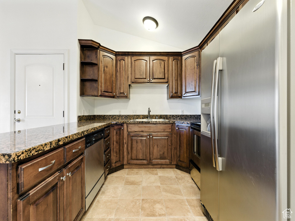 Kitchen featuring appliances with stainless steel finishes, open shelves, lofted ceiling, dark stone counters, and a peninsula