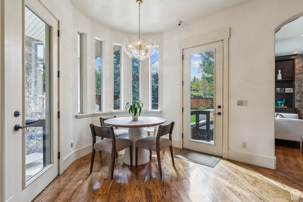Dining space featuring wood finished floors, a chandelier, and arched walkways