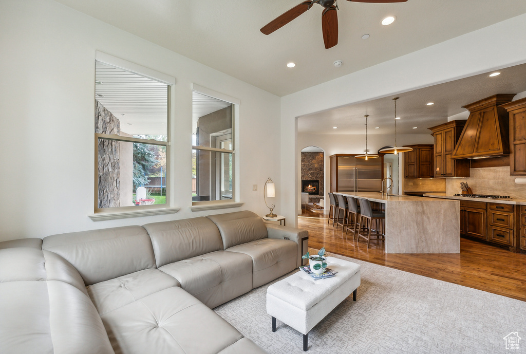 Living area featuring arched walkways, a ceiling fan, recessed lighting, and wood finished floors