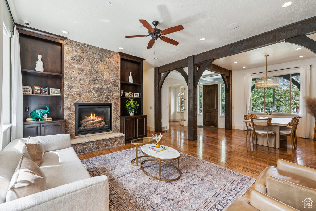 Living area featuring arched walkways, a ceiling fan, wood finished floors, recessed lighting, and a fireplace