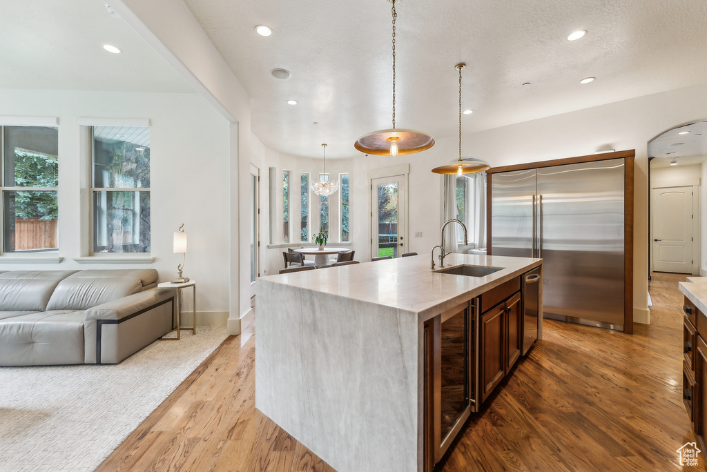 Kitchen featuring stainless steel appliances, light wood-style floors, beverage cooler, open floor plan, and recessed lighting