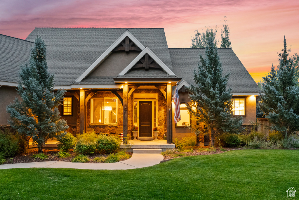 Craftsman inspired home with roof with shingles, a yard, and a porch