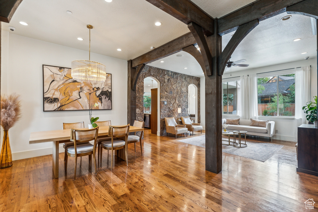 Dining area with arched walkways, wood finished floors, ceiling fan, beamed ceiling, and recessed lighting