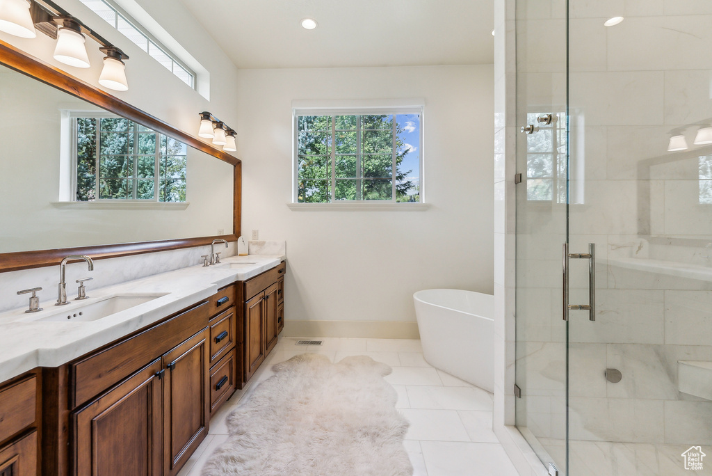 Bathroom with double vanity, a stall shower, a freestanding bath, tile patterned flooring, and recessed lighting