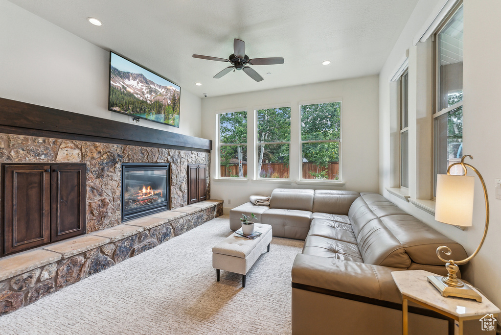 Living room featuring ceiling fan, a stone fireplace, and recessed lighting