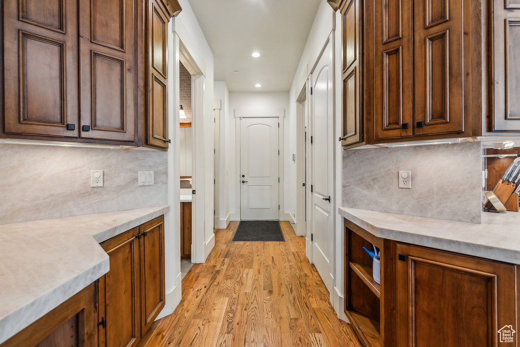 Kitchen with decorative backsplash, light wood-type flooring, light countertops, and recessed lighting