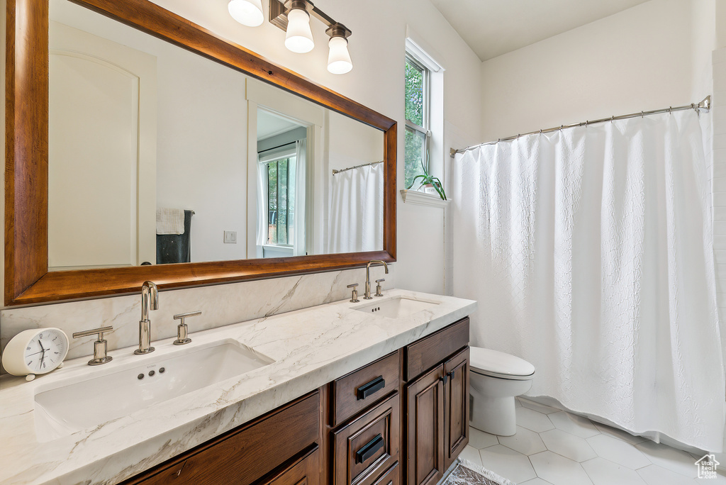 Bathroom with double vanity, tile patterned flooring, and curtained shower