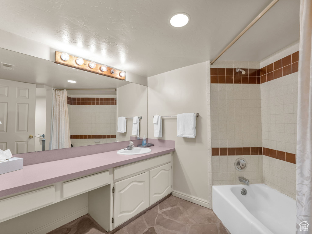 Full bath with shower / bath combination with curtain, vanity, and tile patterned flooring