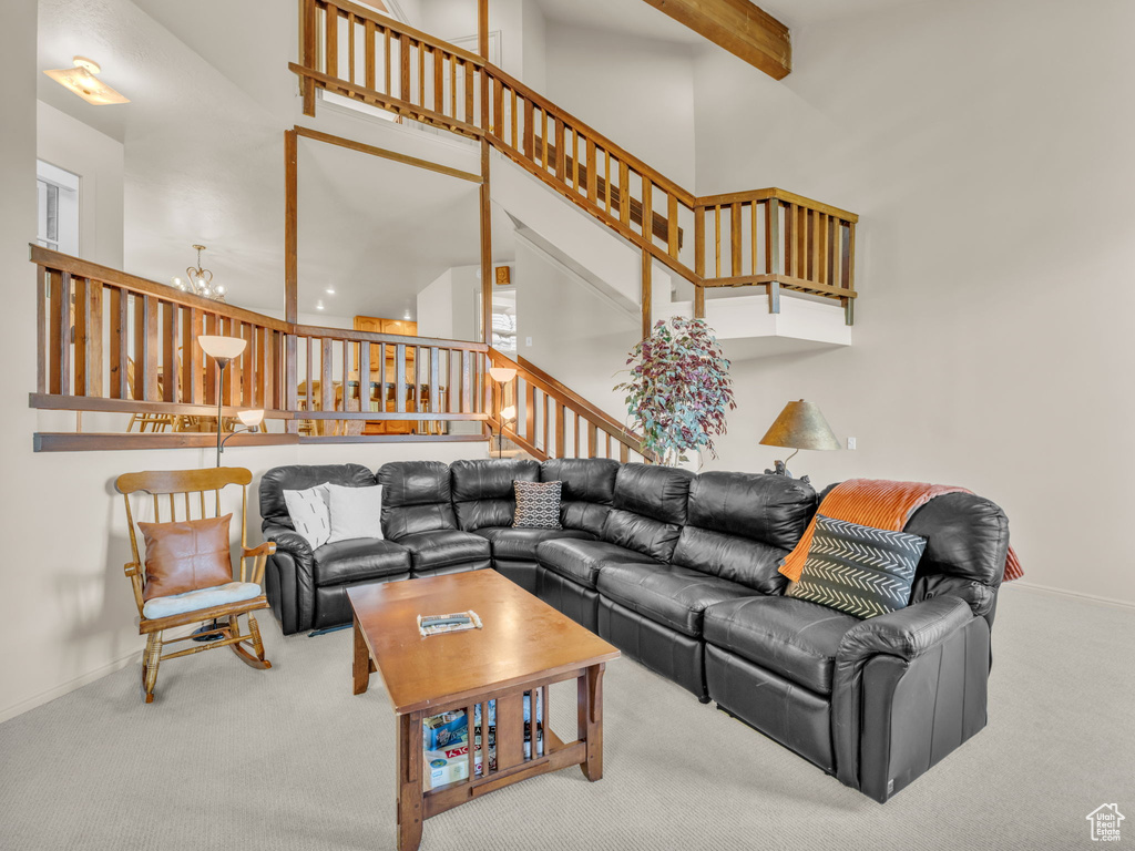 Carpeted living room with a towering ceiling, stairs, and beamed ceiling