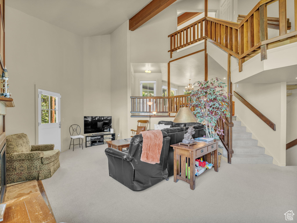 Carpeted living area with a towering ceiling, stairway, and beamed ceiling