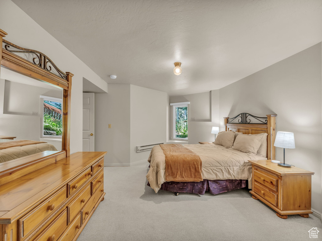 Bedroom featuring light carpet and baseboard heating