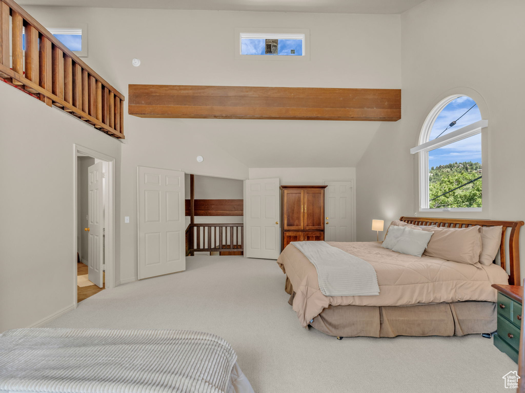 Bedroom with a high ceiling, carpet floors, and beamed ceiling