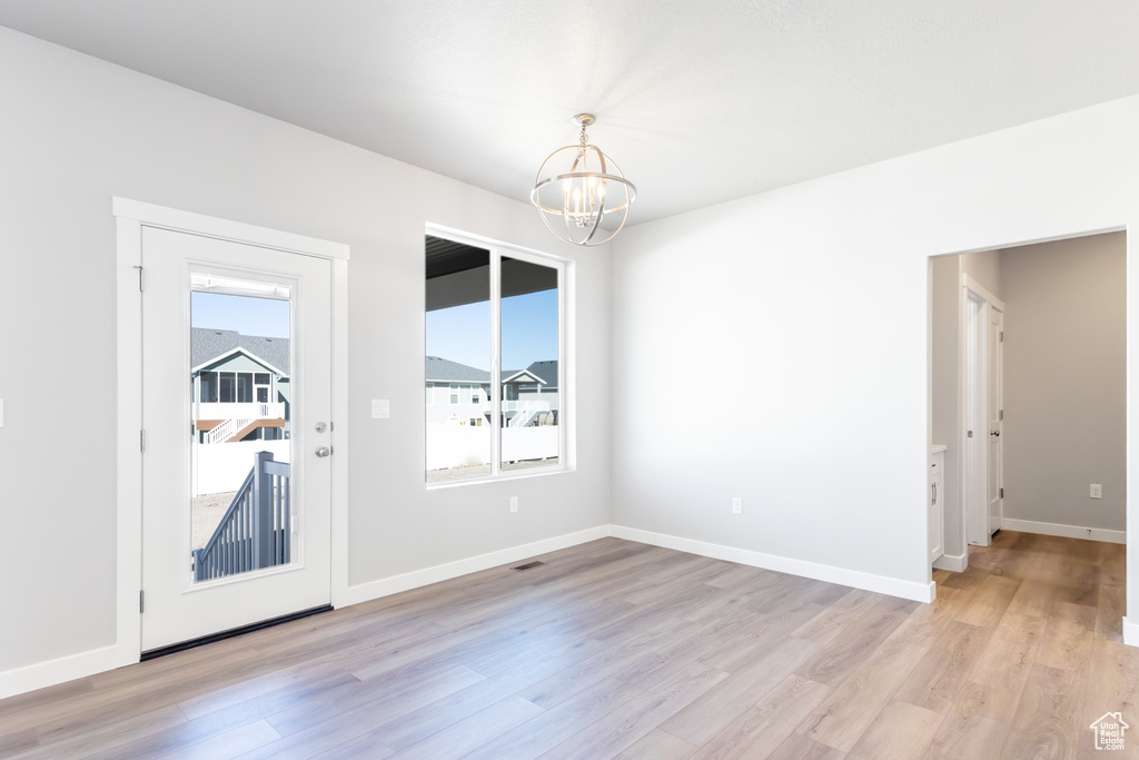 Empty room with a chandelier and light wood finished floors