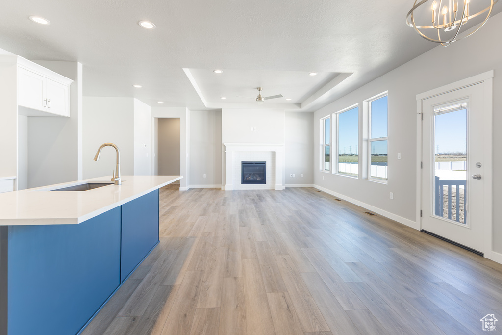 Kitchen with a raised ceiling, a ceiling fan, recessed lighting, light wood finished floors, and light countertops