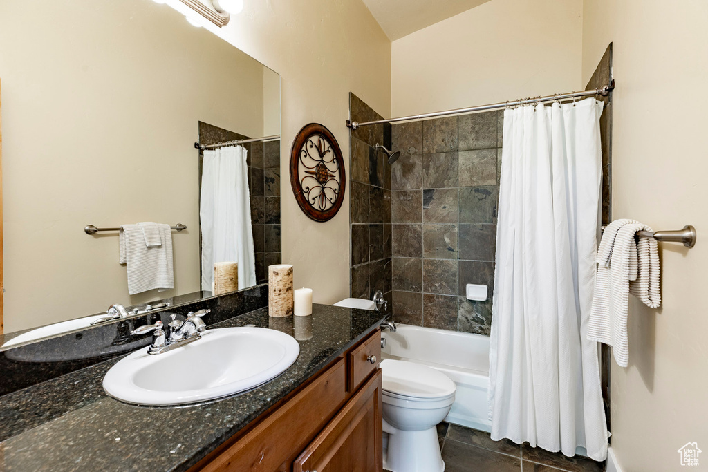 Full bathroom featuring vanity, shower / bath combo with shower curtain, and tile patterned flooring