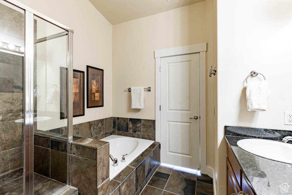 Full bathroom featuring a stall shower, a bath, and vanity