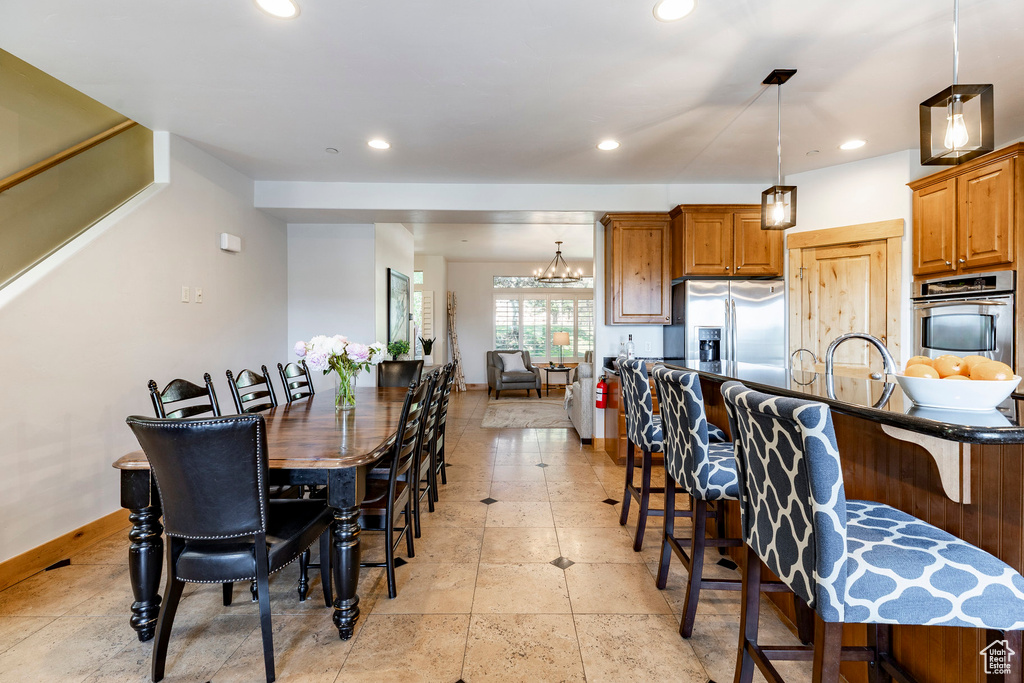 Kitchen with stainless steel appliances, a kitchen breakfast bar, recessed lighting, dark countertops, and decorative light fixtures