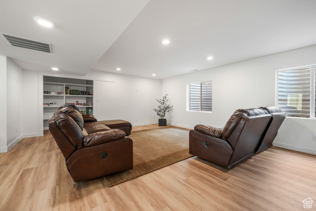 Living area with light wood-type flooring and recessed lighting