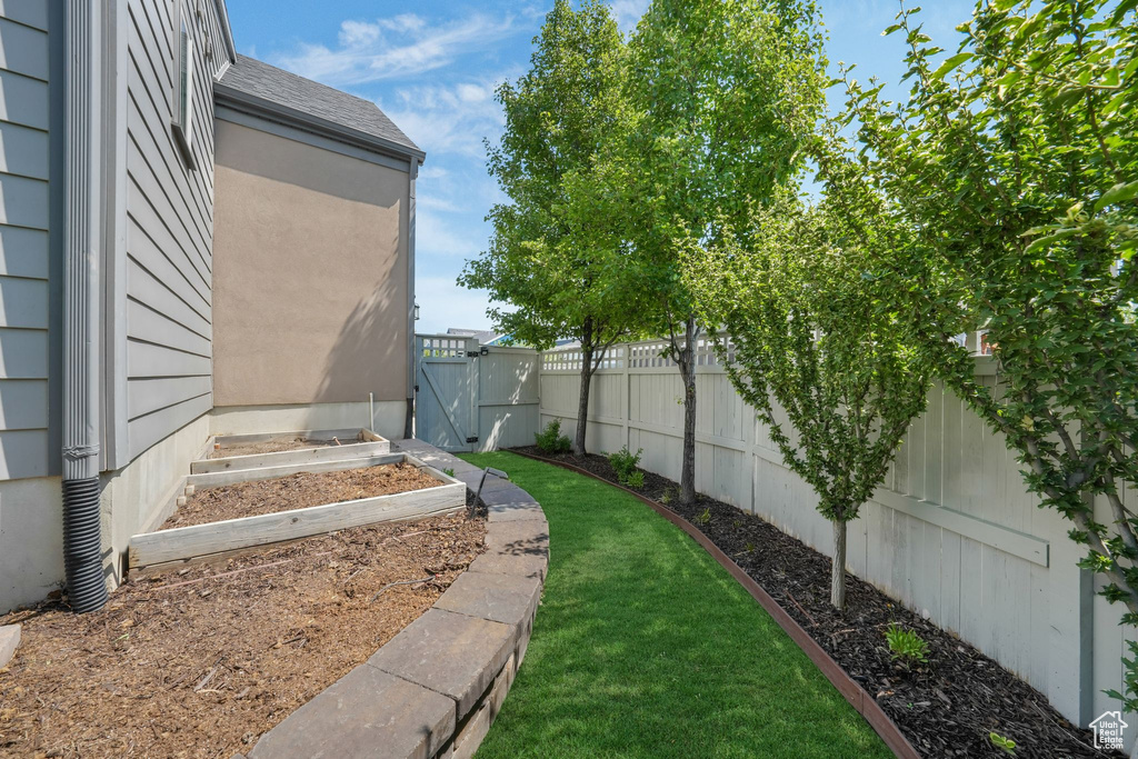 Fenced backyard featuring a gate and a vegetable garden