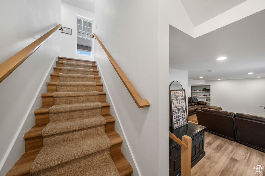 Staircase with wood finished floors, recessed lighting, and a high ceiling
